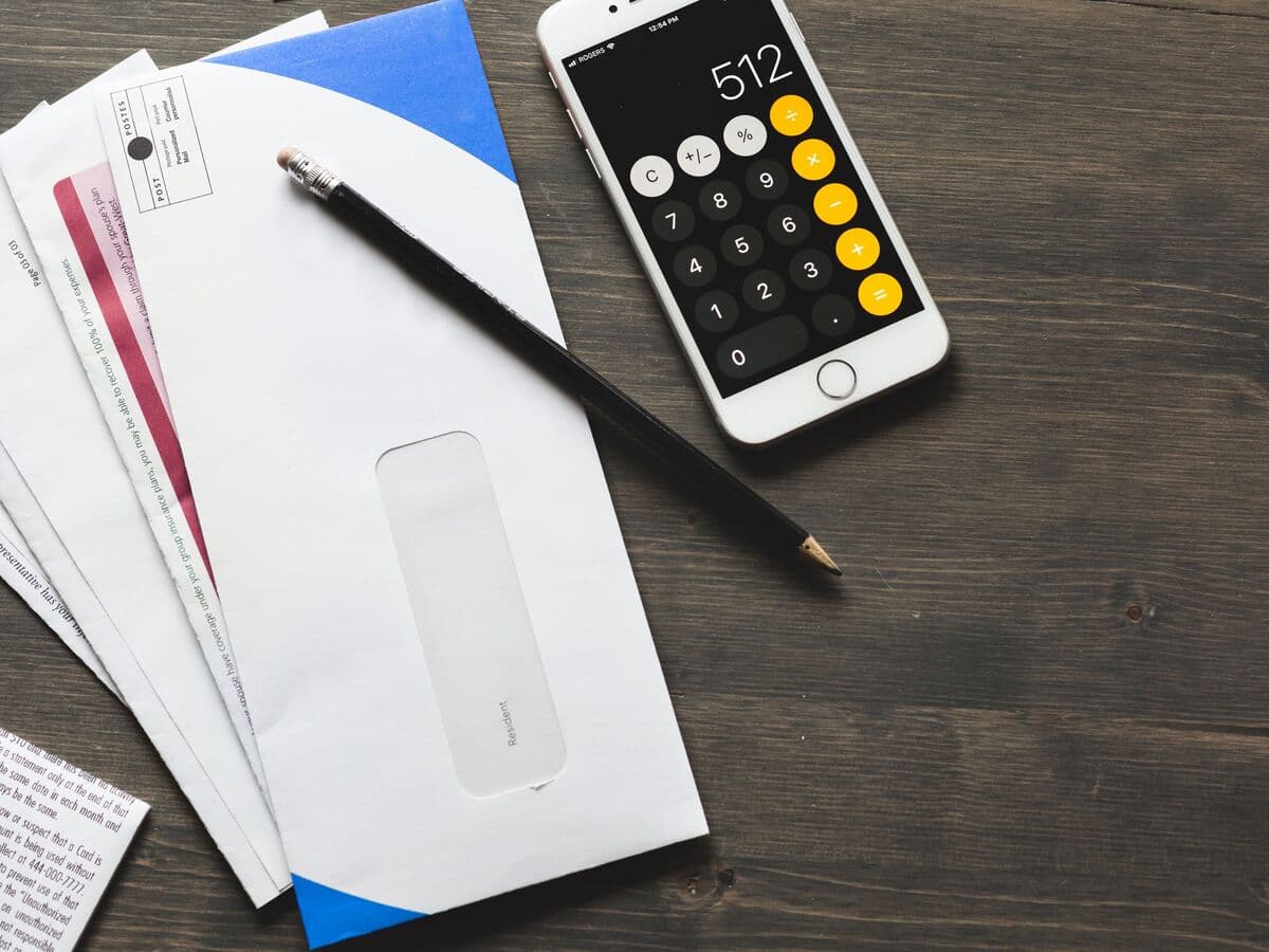 Bills in envelopes beside a phone calculator